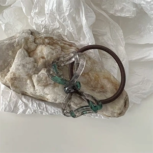 Detail of elegant acetate bow hair tie with dark green marble pattern on stone base
