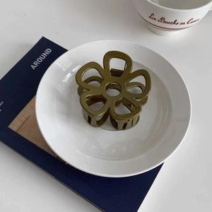 Dettaglio della pinza per capelli a fiore verde oliva su piatto di ceramica