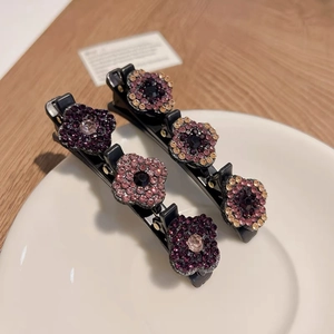 Vue détaillée de pinces à cheveux fleur en cristal avec strass dégradés sur pinces noires