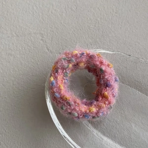 Detailed macro view of pink knit scrunchie with colorful yarn flecks and fuzzy texture