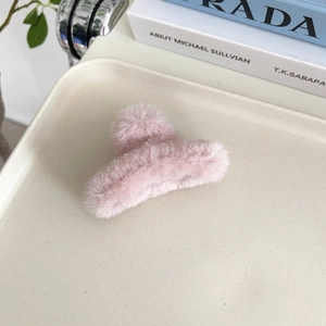 Detail der rosa Plüsch-Haarklammer aus Kunstpelz auf ästhetischem cremefarbenem Tablett