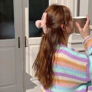 Detail view of large pink plush hair claw clip styled in a half-up bun hairstyle
