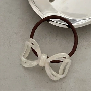 Detail of elegant acetate bow hair tie with marble texture on minimalist background