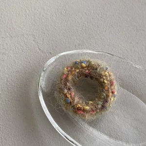 Detail of soft knit tweed scrunchie with colorful specks on a glass display dish