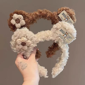 Close-up of plush lamb wool headbands in brown and beige with knit flower details