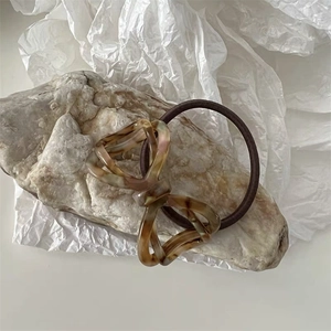 Detailed shot of an amber acetate bow hair tie on a natural textured stone surface