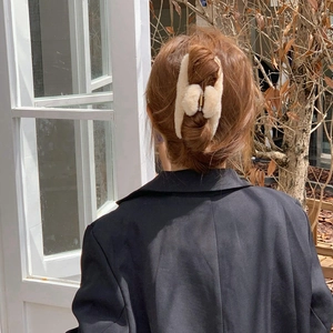Detail view of large beige plush shark hair claw clip on model's head for autumn winter