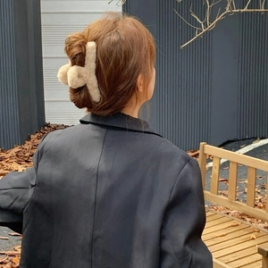 Detail of large beige plush claw clip holding thick hair in an elegant updo hairstyle