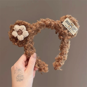Detailed view of plush brown bear ear headband with knit flower and woven label