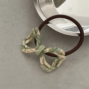 Macro shot of acetic acid butterfly hair tie with light green marble texture