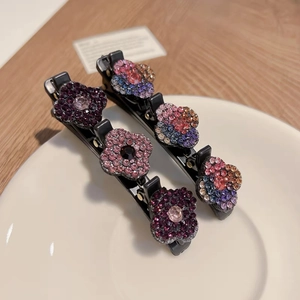 Détail de barrettes à cheveux ornées de fleurs en cristal coloré sur une assiette