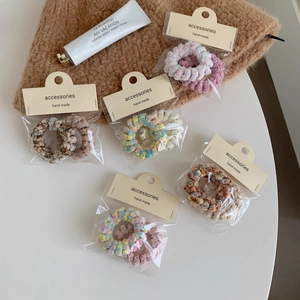 Détail de cinq chouchous en peluche aux couleurs pastel avec un emballage de vente élégant