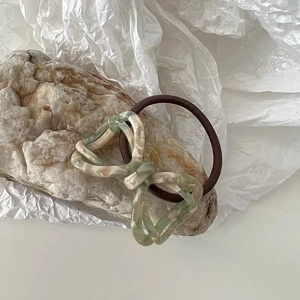 Macro shot of acetic acid hollow bow hair tie with marble texture on stone base