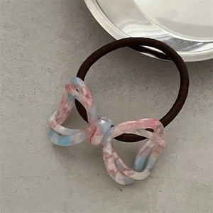 Close-up of pink and blue acetate bow hair tie with marble texture on grey background