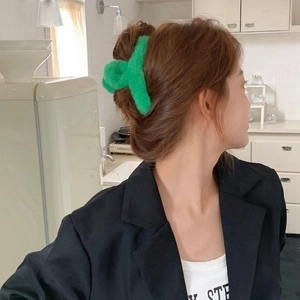 Close-up of a vibrant green plush shark hair claw clip worn on a woman's head