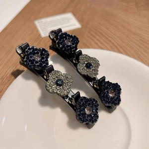 Vue détaillée de deux pinces à cheveux fleurs étincelantes avec strass sur assiette blanche