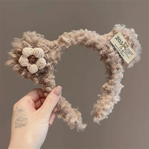 Detailed macro view of soft brown plush bear ear headband with a knitted flower detail