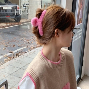 Side view of a large pink plush shark hair claw clip worn on head for thick hair styling