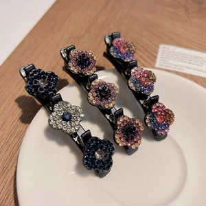 Vue détaillée de trois barrettes à fleurs en strass étincelants sur un plateau en céramique