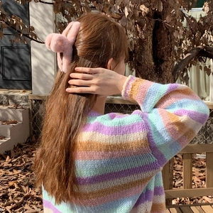 Close-up of a large pink plush shark hair claw clip styled on a model in autumn scenery