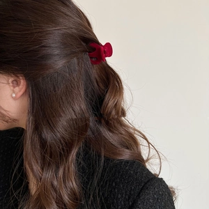 Detail view of a dark red flocked velvet hair claw clip on dark brown curly hair