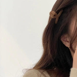 Detail view of dark brown flocked hair claw clip on brunette wavy hair for styling