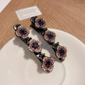 Détail de pinces à cheveux florales avec strass violets sur une assiette blanche