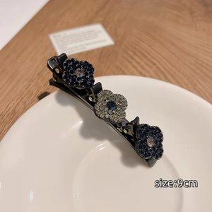 Détail d'une pince à cheveux fleurie bleu marine de 9cm avec strass étincelants