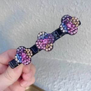 Détail d'une pince à cheveux noire ornée de trois fleurs étincelantes en strass multicolores
