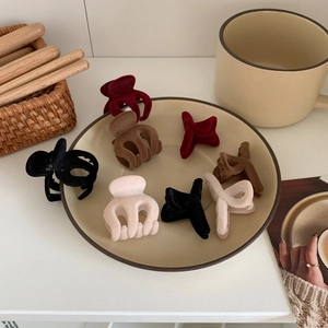Set of mini flocked velvet hair claws in dark tones displayed on a ceramic plate