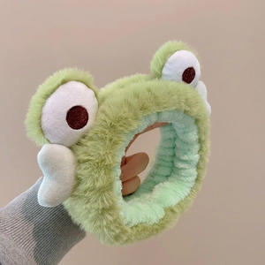 Close-up of soft green plush frog headband showing fuzzy texture and cute big eyes