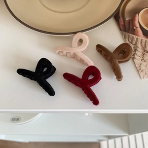 Four vintage flocked hair claws in black, pink, wine red, and brown on white surface