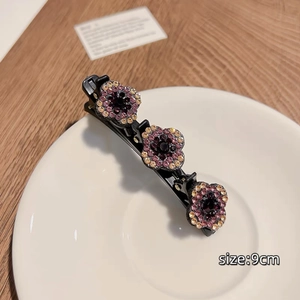 Détail de la pince à cheveux de 9cm avec trois fleurs en strass violets et rouges élégants