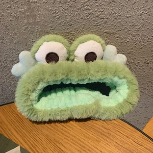 Detailed texture of green plush frog headband with soft coral fleece material for facial care