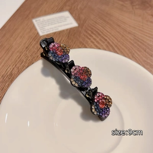 Détail d'une pince à cheveux de 9cm avec des fleurs en strass colorés sur métal