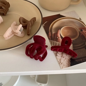 Detailed view of flocked velvet hair claws in burgundy and brown tones on a ceramic plate