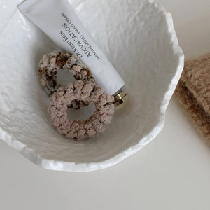 Détail d'élastiques à cheveux en maille pelucheuse beige et marron dans un bol en céramique