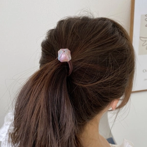 Élastique à cheveux avec breloque géométrique en résine rose porté en queue de cheval