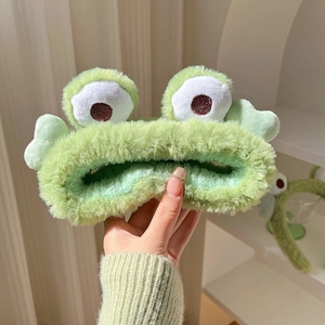 Close-up of soft green plush frog headband showing plush texture and cute eyes
