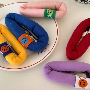 Close-up of colorful puffy cloth hair clips with smiley face ribbons in a white ceramic dish