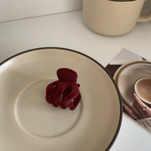 Macro detail of wine red velvet hair claw clip on a minimalist ceramic plate tray