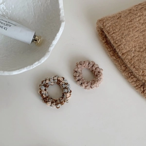 Détail de deux chouchous spirales en peluche tricotée marron et crème pour l'automne