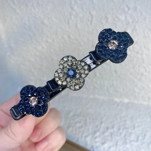 Détail de trois fleurs en strass sur une longue pince à cheveux avec des pierres bleues