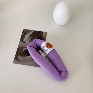 Detailed view of a purple fabric BB hair clip with a smiling face and 'C' letter print