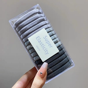 Macro shot of grey gradient high elasticity hair ties in a clear rectangular plastic box
