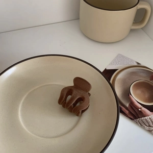 Detail shot of a brown velvet hair claw clip on a ceramic plate for elegant styling