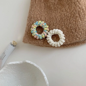 Détail d'élastiques spirale en peluche tricotée colorés et beige sur un bonnet d'hiver