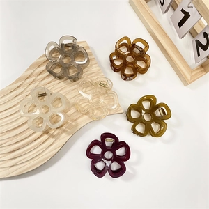 Dettaglio di sei pinze per capelli a fiore colorate su un vassoio decorativo in legno