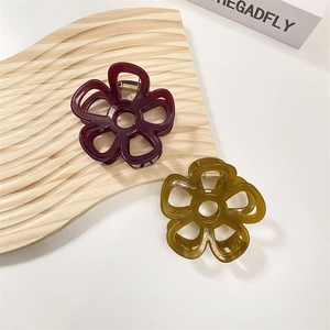 Dettaglio di mollette per capelli a forma di fiore in resina bordeaux e verde ambra