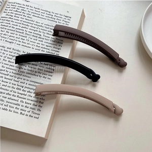 Three-piece matte banana hair clips in mocha and black tones on a vintage book page